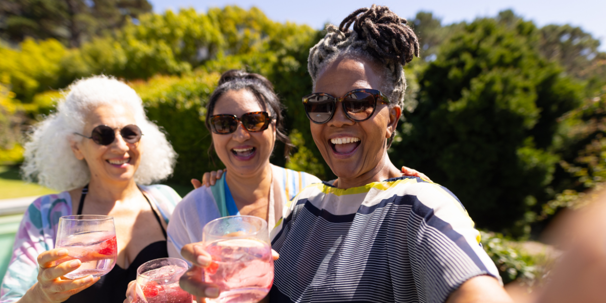 Three women friends laughing and socialising outdoors